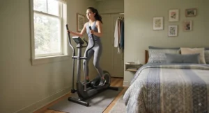 Person using a space-saving elliptical machine in a cozy bedroom with limited floor space.
